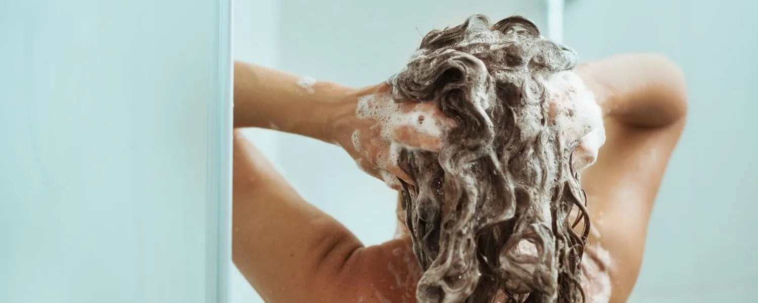 Kvinnan tvättar håret med schampo för fett hår