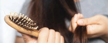 Kvinna med en hårborste fylld med hår
