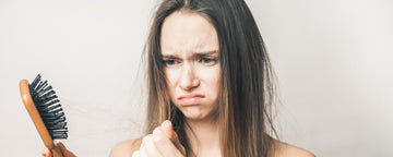 Flicka med håravfall tittar på hennes hårborste