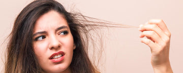 Kvinna tittar på hennes tunna hår